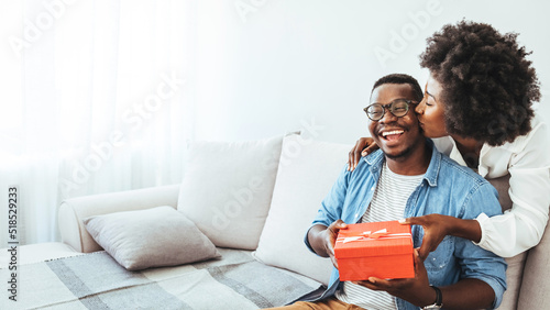 Young couple with gift box hugging at home. Valentine's Day concept. Happy couple in love with. A young loving couple celebrating Valentine's Day at the home. Lovers give each other gifts. 