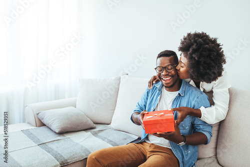 Valentine's day. Couple gives gift box to the Valentine's Day in the room. Beautiful young couple at home. Hugging, kissing and enjoying spending time together while celebrating Saint Valentine's Day 