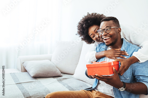 Valentine's day. Couple gives gift box to the Valentine's Day in the room. Beautiful young couple at home. Hugging, kissing and enjoying spending time together while celebrating Saint Valentine's 