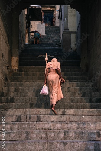 Vertical back view of a female climbing the stairs of Varanasi Ghats