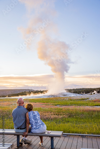 Old couple watching the Old Faithful geyser during sunset