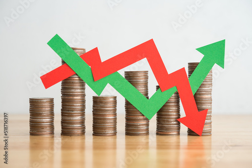 Stack coins and arrow red green graph chart volatility up and down on wooden table background. Business, financial and investment concept. Risk, fluctuation in stock market and cryptocurrency.