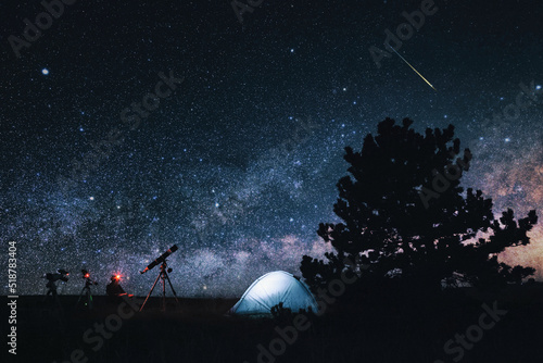 Amateur astronomer with astronomical telescope camping in nature under the Milky way stars.