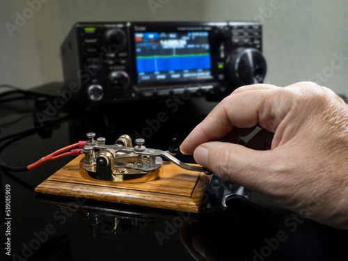 Selective focus of man's hand on a telegraph key with radio defocused in background