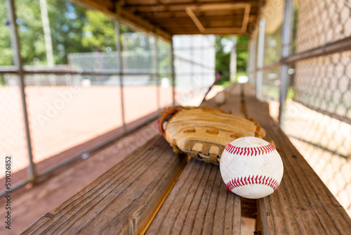 Baseball with glove on dugout bench with blurred background