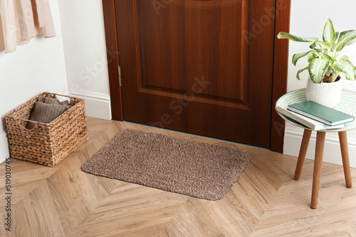 Clean door mat on wooden floor in hall