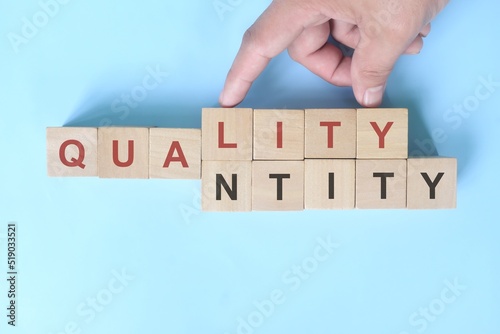 Quality over quantity concept. Hand changing word quantity to quality on wooden blocks.