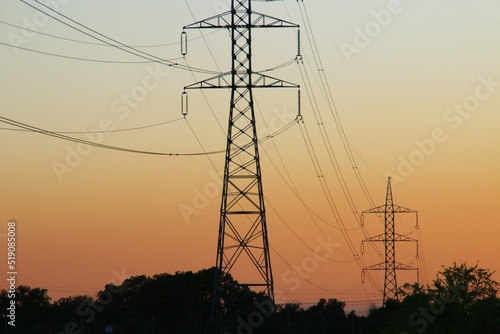 Silueta de torres de alta tensión para la conducción de electricidad. Imagen tomada al atardecer con los últimos rayos del sol mientras se pone en el horizonte. Madrid, España.