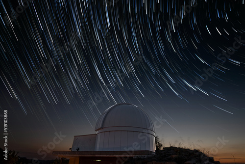 Astronomical observatory under star trails sky at night