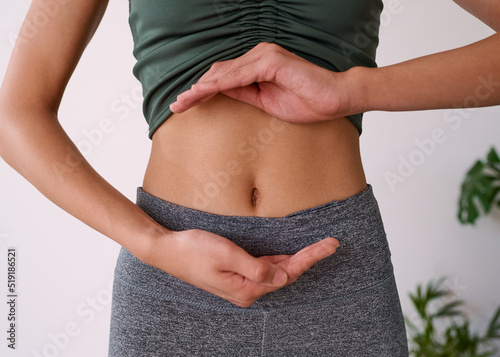 Close up of a young multi-ethnic woman's stomach cupped by her hands