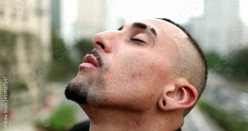 Hispanic man closing eyes looking to sky with hope and faith