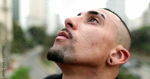 Hispanic man closing eyes looking to sky with hope and faith