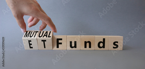 Mutual funds vs ETF symbol. Businessman hand turns a cube and changes words ETF 'Exchange-Traded Fund' to Mutual funds. Beautiful grey background. Business and ETF vs mutual funds concept. Copy space