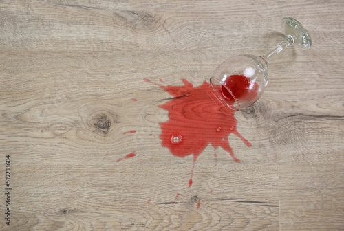 Glass of red wine fell on laminate, wine spilled on floor.