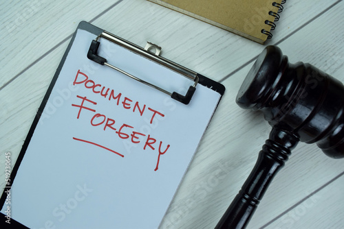 Concept of Document Forgery write on a paperwork with gavel isolated on Wooden Table.