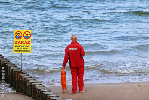 Ratownik na plaży podczas patrolowania brzegu wody nad morzem latem. 