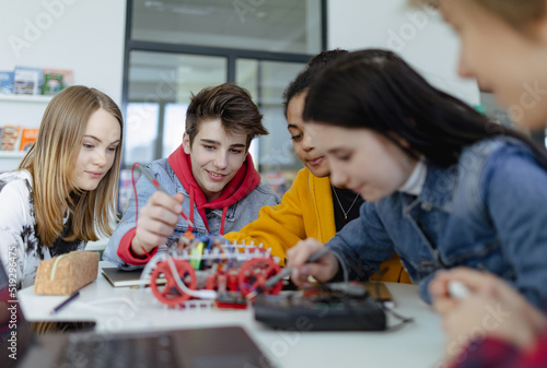 Group of high school students building and programming electric toys and robots at robotics classroom