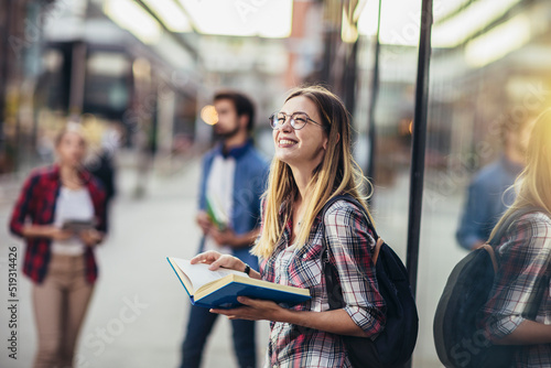 Happy university student going on a class at the university and looking at camera.