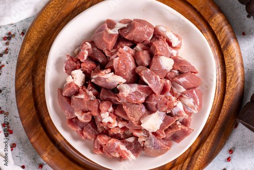 Lamb cubed meat. Chopped red meat in a plate on a stone floor. Butcher products. close up. Top view