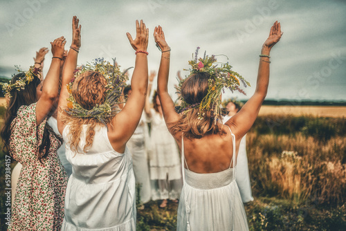 Women in flower wreath on sunny meadow, Floral crown, symbol of summer solstice.