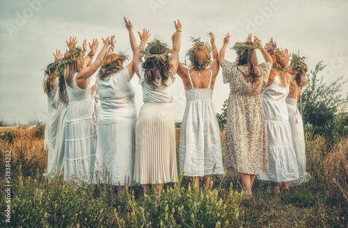 Women in flower wreath on sunny meadow, Floral crown, symbol of summer solstice.