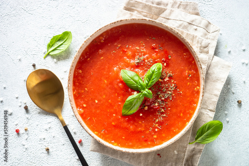 Tomato soup with spices and basil. Cold summer soup. Top view on white background.