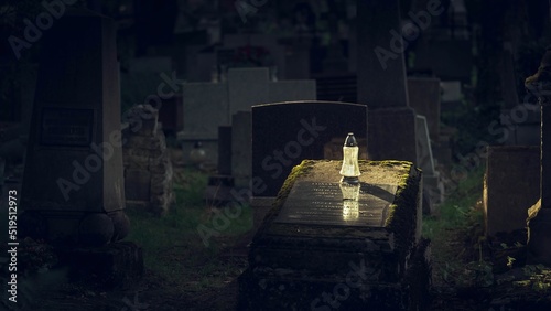Znicz na cmentarzu postawiony na grobowcu - pada na niego słońce