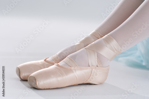 Ballerina in pointe shoes. Ballet posing, performance. Woman's legs with shoes for ballet dancing on white background