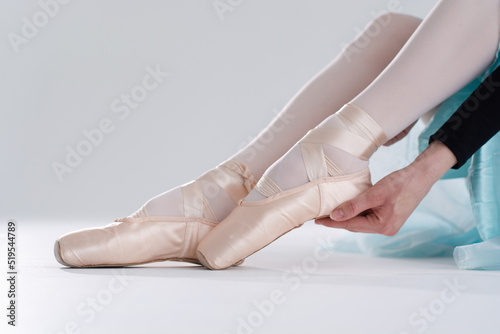 Ballerina in pointe shoes. Ballet posing, performance. Woman's legs with shoes for ballet dancing on white background