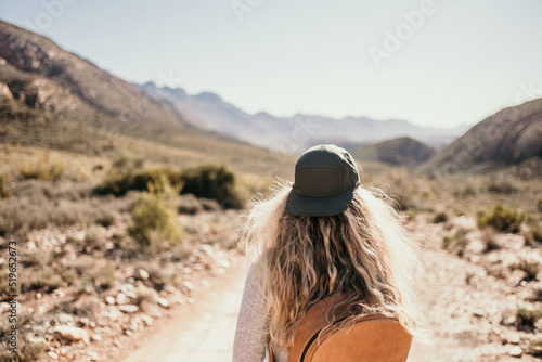 woman walking in karoo desert with cap & blond hair