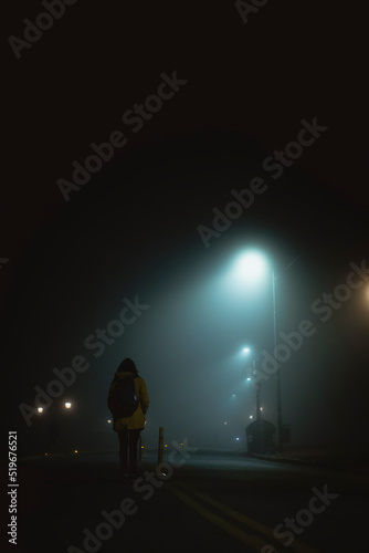 Mujer caminando sola en la noche con niebla