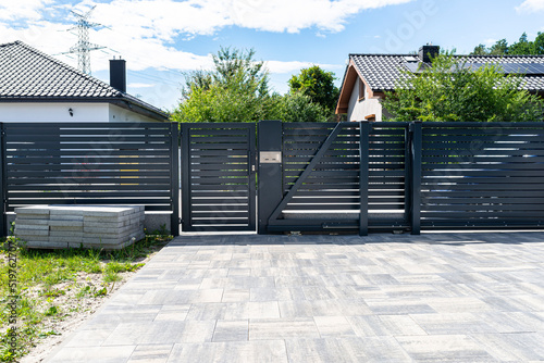 A modern panel fence in anthracite color, a visible sliding gate to the garage and a wicket with a letterbox.