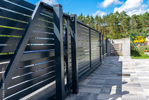 Modern panel fencing in anthracite color, visible sliding gate to the garage as well as a handle and a lock.