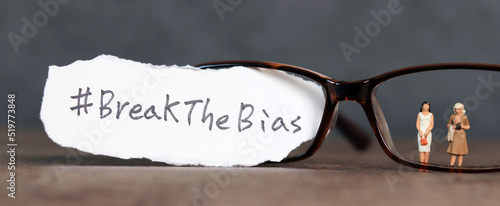 Torn paper with the word ‘BreakTheBias' written on it. Break the bias campaign with miniature women. 