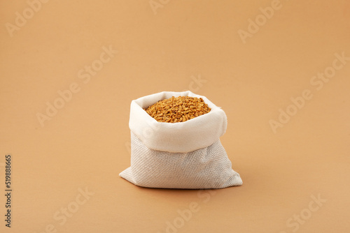 Brown Fenugreek seeds in white pouch. Selective focus, copy space