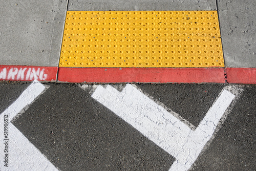 Freshly painted white crosswalk marking leading to a yellow painted ADA sidewalk access in a fire lane 