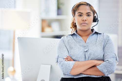 Serious female customer service worker with headphones at the office at a call center. Portrait of an IT tech support agent dedicated to helping customers. Closeup of a woman standing at a desk