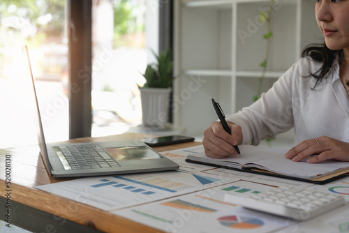 business woman taking note and using laptop for accounting financial.