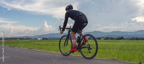 Professional cyclist in cycling training suit against green nature blur background Healthy fitness and lifestyle concepts.