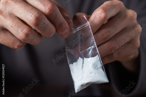 Concept drug addiction. Man hand holds plastic packet or bag with cocaine or another drugs