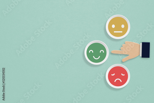 customer feedback, rating, evaluation, vote concept. businessman hand point at happy face on paper cut with grunge green background including copy space