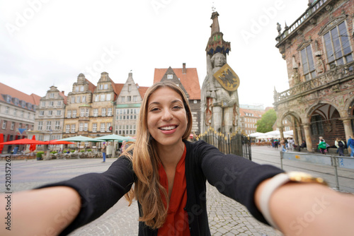 Self portrait of young woman in Bremen Market Square with Roland statue, Germany