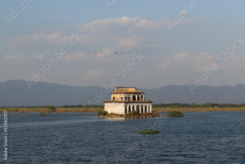 Abandoned, mysterious old house left on a little island surrounded by water