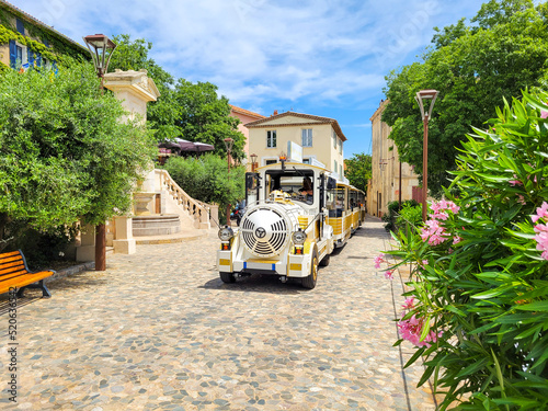 The gold and white tourist train that runs from the town of Saint-Tropez as it stops at it's destination in the old hilltop medieval village of Grimaud, France.