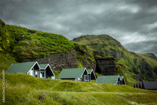Paisaje Islandia, casas y cabaña tejado verde con montañas de fondo