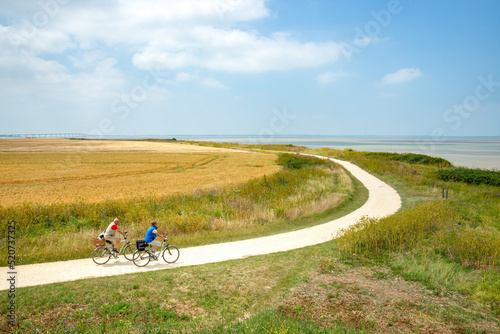 Two senior tourists cycling on Atlantic coastal path at La Rochelle, Charente-Maritime, France