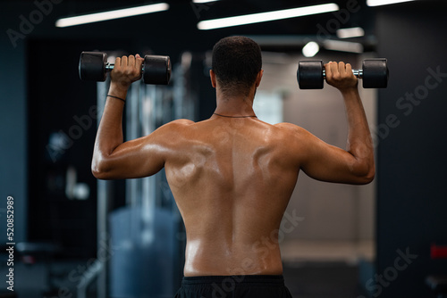 Back View Of Athletic Black Man With Naked Torso Exercising With Dumbbells