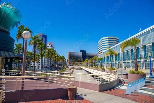 a gorgeous summer landscape at the Long Beach Convention Center with tall lush green palm trees and skyscrapers and office buildings in the skyline with blue sky in Long Beach California USA