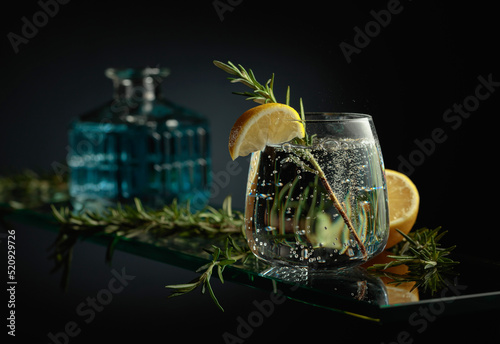 Gin tonic cocktail with lemon and rosemary.