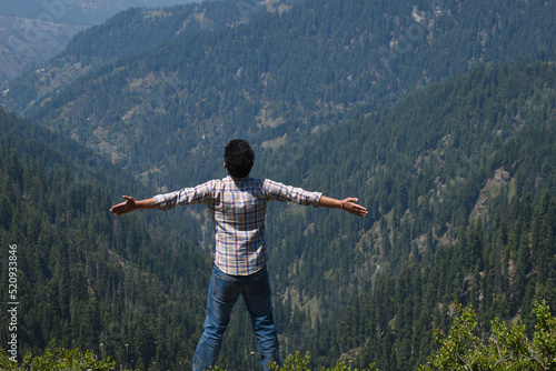 Adventurous guy outstretched arms outdoor himalayan cedar mountain forest in background